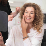 Woman examining sagging jowls during facial consultation for jowl lift treatment in a cosmetic clinic.