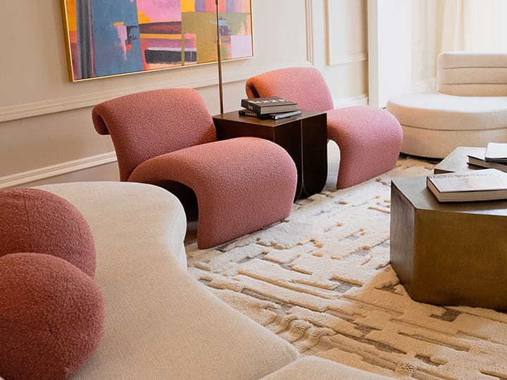 Stylish clinic lounge area with curved pink and cream chairs, abstract artwork, and modern furnishings.